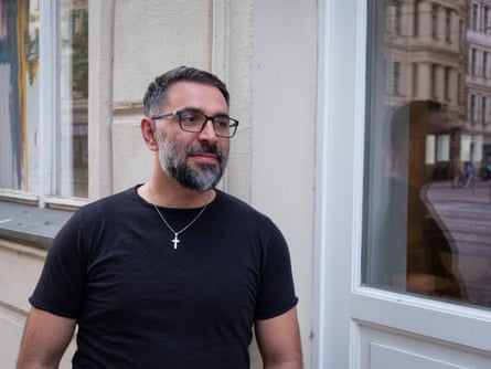 Hamid in a black T-shirt wearing a silver chain and cross