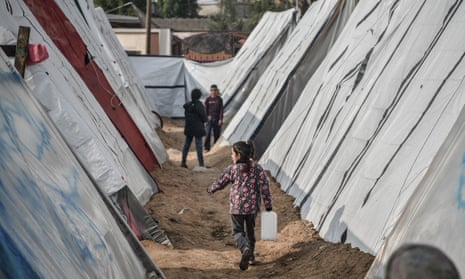 A Palestinian child is seen carrying water as Palestinian families fleeing Israeli attacks on Gaza, setting up makeshift tents in empty areas to ensure their safety in Rafah