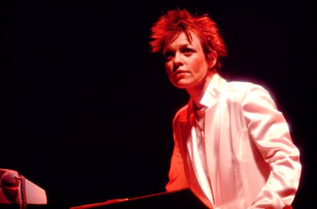 A woman with her short hair highlighted, in concert.