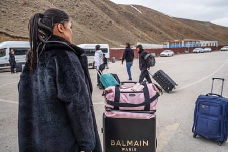 A woman stands near a Balmain suitcase