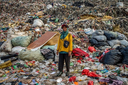 Rustini, 48, stands in front of one of the towering mounds of waste at the Bantar Gebang landfill