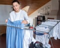 A Woman Hanging Laundry On Drying Rack In Room