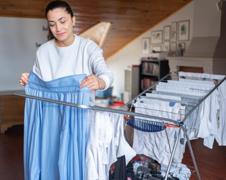 A Woman Hanging Laundry On Drying Rack In Room