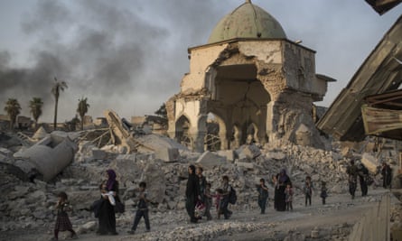 Women and children file past the heavily damaged al-Nuri mosque as they flee Mosul in July 2014.