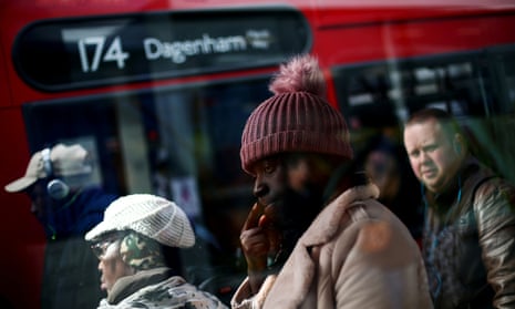 Travellers queue for a bus on a high street in Dagenham, east London.