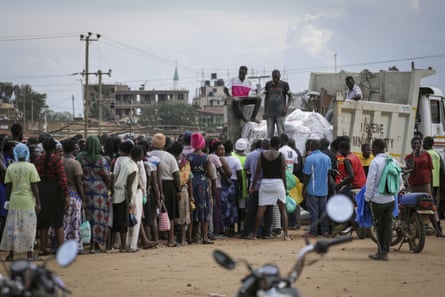 People line up as food is handed out from a truck.