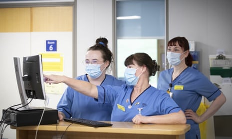 Three nurses look at a computer monitor