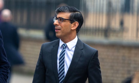 Rishi Sunak in a suit and tie on the street, looking at something off camera