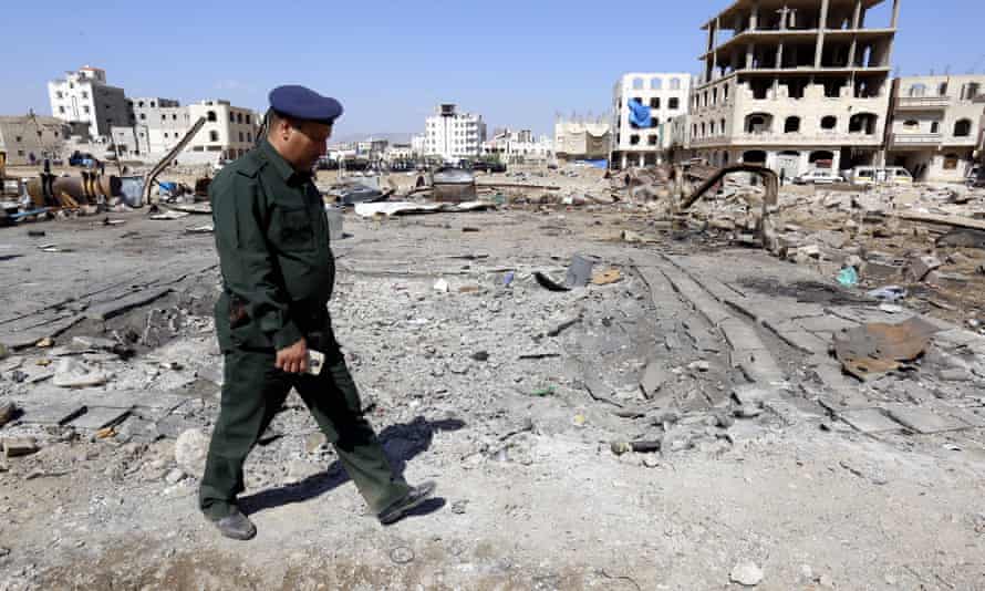 A Yemeni police officer inspects the site of an alleged Saudi-led airstrike, damaging nearby schools.