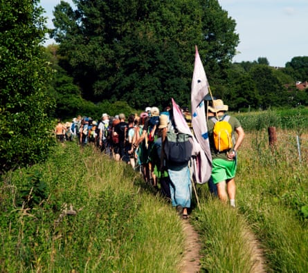 People pictured from behind walking along a path, some holding flags.