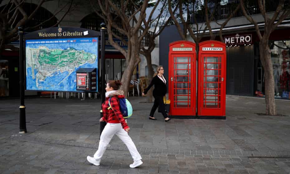 Women walk past red telephone boxes in the centre of Gibraltar.