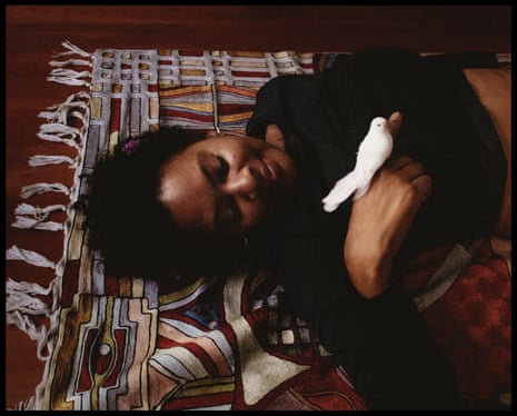 a woman holds a play bird while laying on a rug