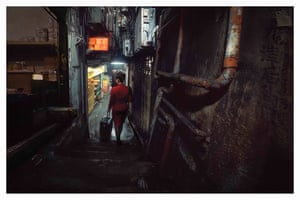 Bianca Tse, AI Image, Untaken Photo #2, Hong Kong 2024âI mentioned to Bianca Tse that there was an image I canât get out of my head, but it was something I wasnât able to take a photograph of. Iâd seen a Cathay Pacific stewardess, in the distinctive red Cathay uniform, alight from a taxi and, pulling her suitcase behind her, walk into one of the Walled Cityâs alleyways. I raced to follow her but she disappeared. Bianca managed to translate that memory into one of her AI augmented images that so delicately and uncannily balances the real, the remembered and the imagined.â Greg Girard