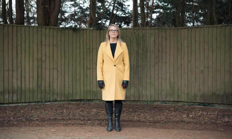 Julie Highfield, a clinical psychologist
who works in critical care, in yellow coat, standing against a fence