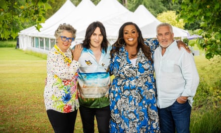 Prue Leith with her hand on Noel Fielding’s shoulder next to Alison Hammond with her arm around Paul Hollywood’s shoulder all standing in a field with tents behind them
