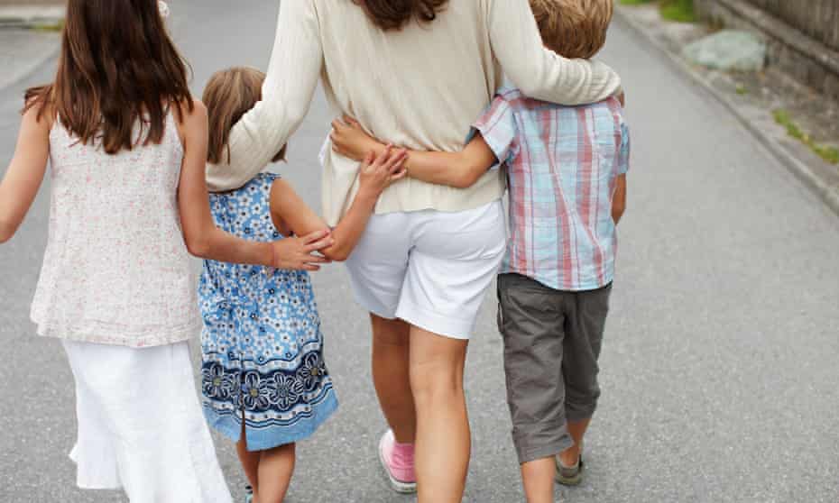 mother with three children walking and hugging