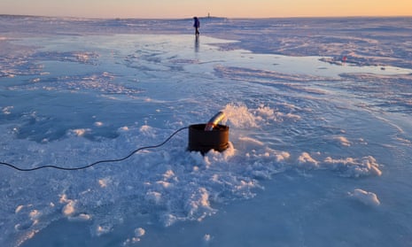 A man in the distance with a pipe spouting water coming out of an oil drum in the foreground