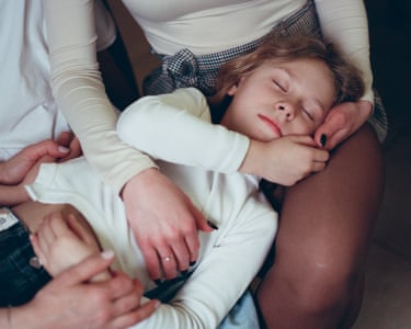 A sleeping girl with her head in a woman's lap