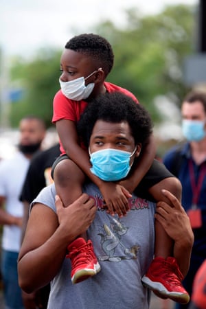 Houston, Texas A young boy sits on the shoulders of a man, both wearing facemasks, during a ‘Justice for George Floyd’ event