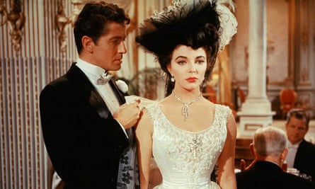 Joan Collins in an elaborate hat and lacy white dress with Farley Granger in The Girl in the Red Velvet Swing, 1955.
