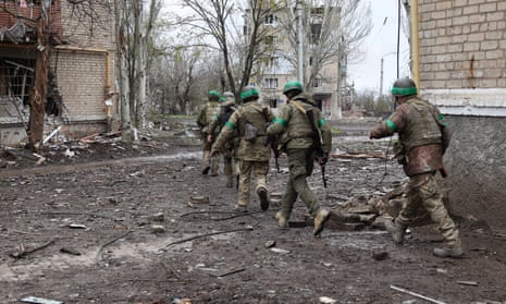 Ukrainian servicemen walk between residential buildings damaged by shelling Bakhmut.