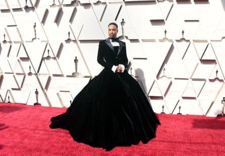 Billy Porter on the red carpet in a tuxedo dress - it is a traditional tux on top but then turns into a full b