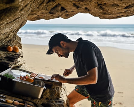 A man in a baseball cap prepares food sheltered from the sun by rocks