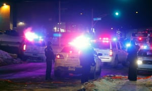 Police officers stand guard near a mosque after a shooting in Québec City on Sunday