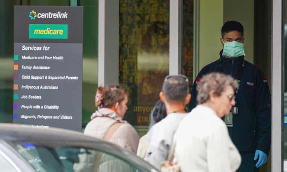 A security guard looks on as people queue outside a Centrelink office