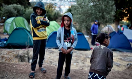 Children stand amid a makeshift tent camp near the overcrowded facility on Samos