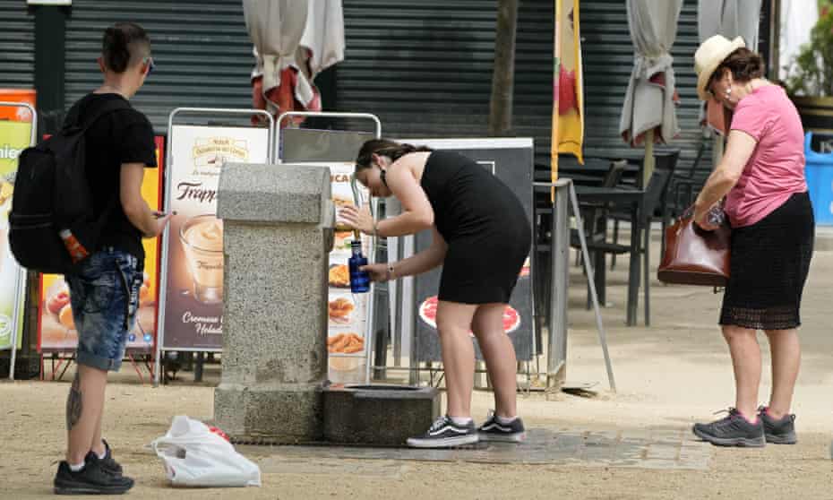People queue for water at a public fountain in the Retiro park in Madrid, Spain.