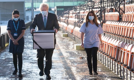 Boris Johnson carrying a bag of coronavirus vaccines at a vaccination centre in north London.