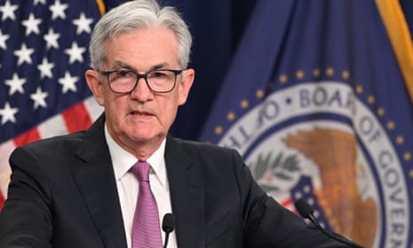 Powell stands in front of US and Federal Reserve flags