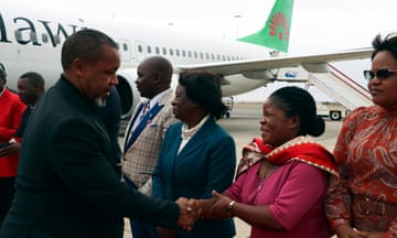 Saulos Chilima shakes people's hands on the tarmac near an airplane
