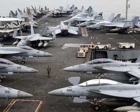 A US Navy officer walks across the flight deck of aircraft carrier USS Abraham Lincoln, lined with fighter jets
