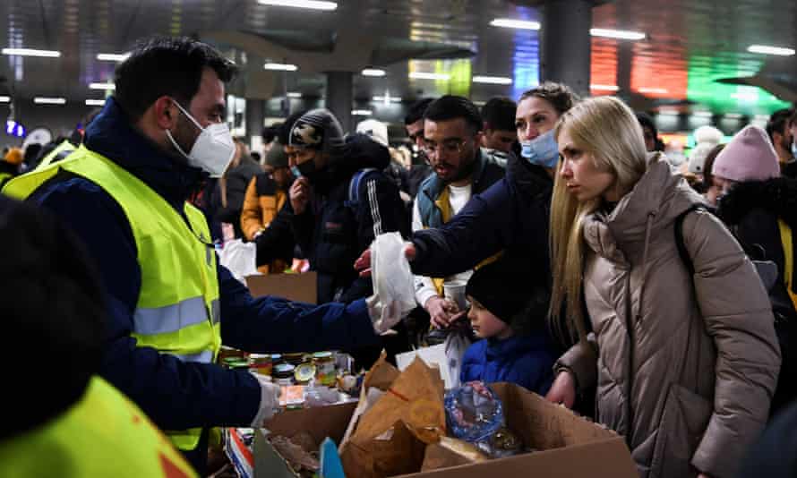 A volunteer hands over food to people from Ukraine at Berlin’s central train station