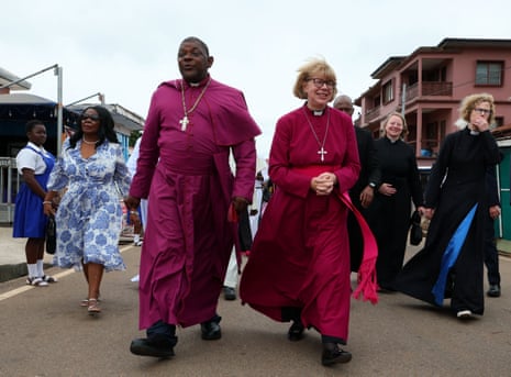 Bishop Cyril Kobina Ben-Smith and Archbishop Sarah Mullally in purple robes walk together on a street, smiling