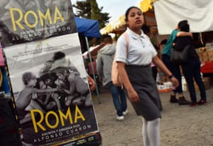 A student walks by a poster for Roma in Tlaxiaco