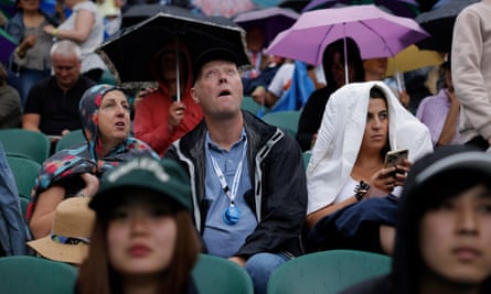 Spectators on Centre Court looking to the skies as rain stops play during day three.
