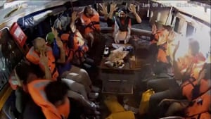 Crew wearing lifejackets hold their hands up