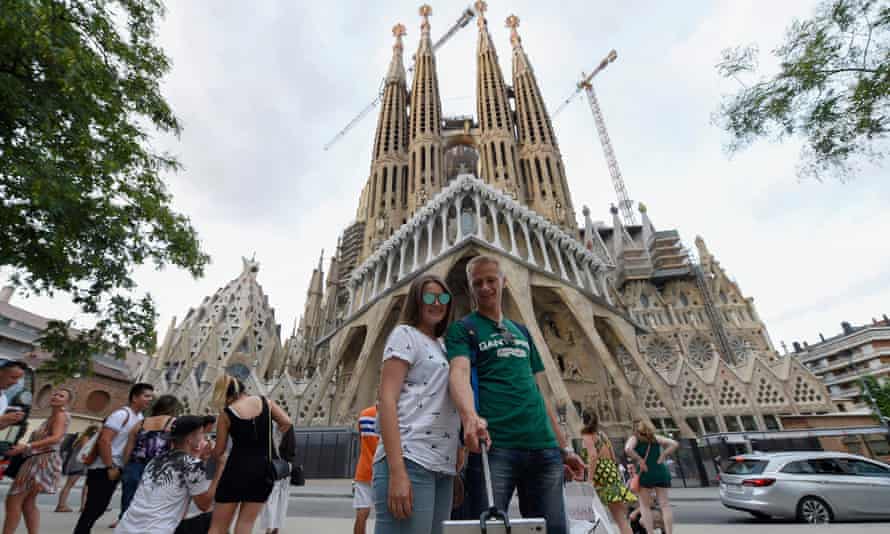 Tourists pose for selfies in front of the Sagrada Familia basilica in Barcelona in August