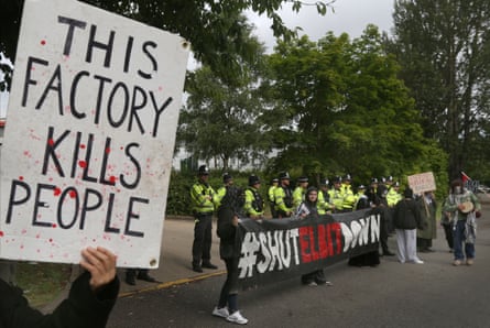 A protester holds up a sign saying ‘this Factory Kills People’ as other protesters block the entrance to the factory during the demonstration.