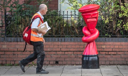 A postal worker walks past a postbox tied in a knot, an artwork by Alex Chinneck in Sheffield