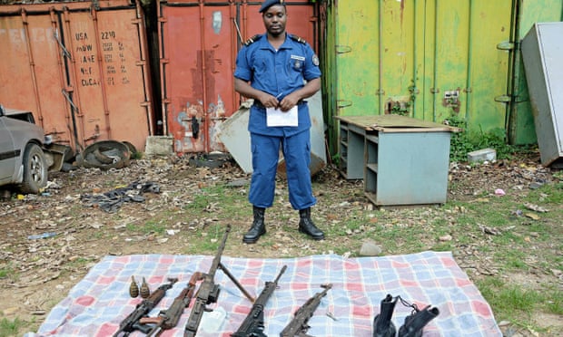 A Burundian policeman displays weapons seized during an operation in the Musaga neighborhood of Bujumbura