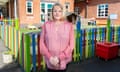 Amanda Richards stands with her hands folded in front of a multi-coloured fence around a school playground