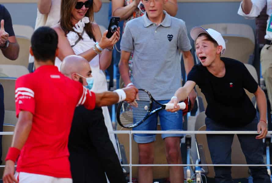 Novak Djokovic hands his racquet to an excited young fan after his victory.