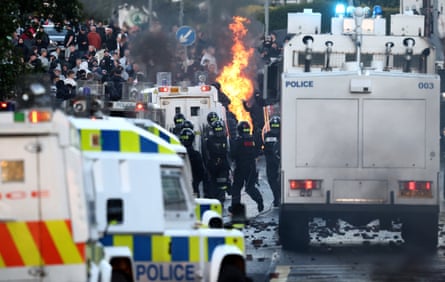 Riot police gather by a fire lit by anti-immigration protesters in Belfast