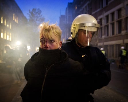 A woman is led away by a police officer.