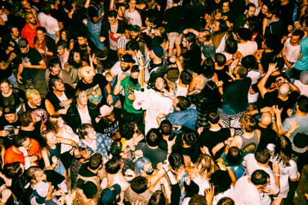 Crowd gathers around man with guitar.