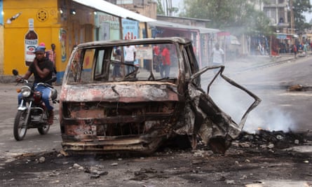 A man rides past a burned-out car in Kinshasa
